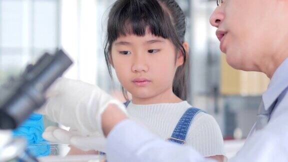 亚洲的小女孩和老师在学校的实验室里观察老鼠学科学的小女孩教育的主题