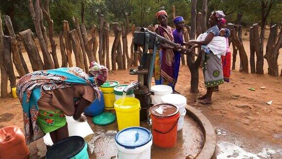 水短缺津巴布韦六名妇女和一名婴儿从公共水泵中将水注入塑料容器中
