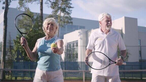 一对快乐的成年夫妇在一个阳光明媚的日子打网球