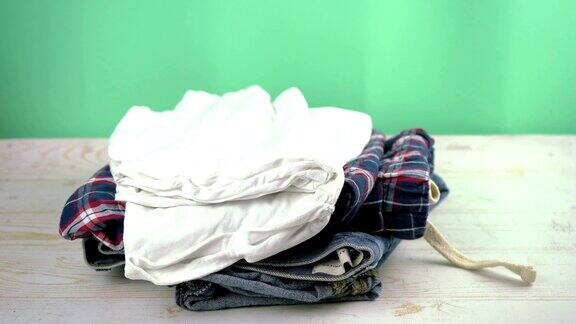 牛仔裤、睡衣、衬衫一堆堆地落在桌子上衣物捐赠或脏衣服概念