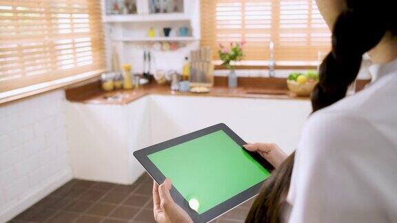 一名女性用绿色屏幕的平板电脑应用程序控制家里厨房的灯智能家居自动化控制概念