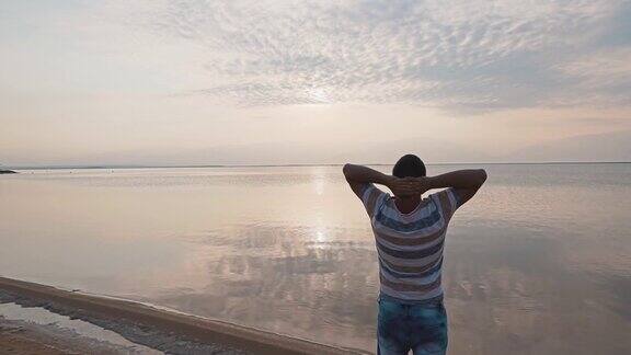 一个年轻人站在死海的岸边欣赏美丽的日出美丽的海景黎明