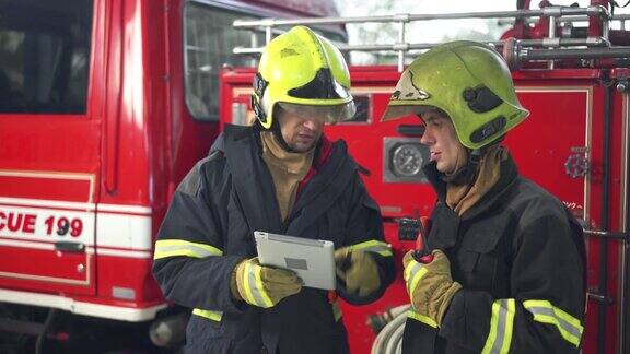 两名男性消防员在消防站使用数字平板电脑工作