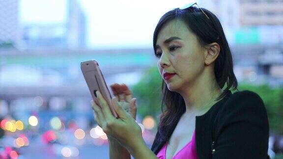 亚洲女商人用夜景手机聊天