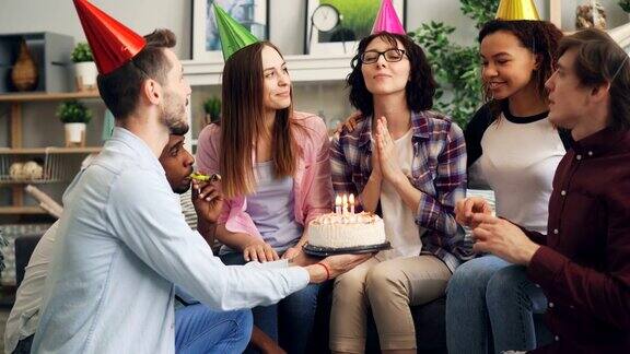 年轻的女士在生日聚会上和朋友吹蜡烛许愿