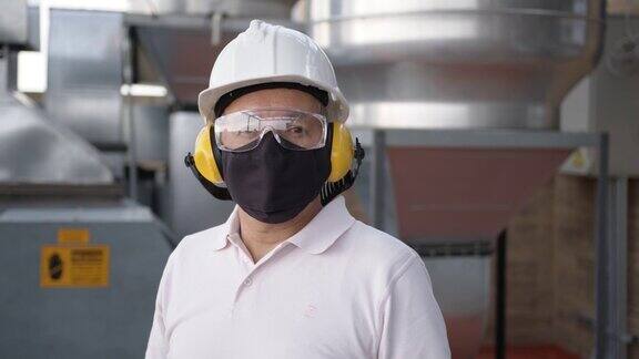 男性主管在工厂的特写镜头戴着护耳护目镜头盔和防护面罩