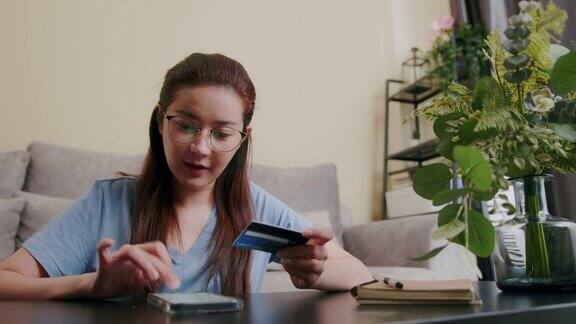 有魅力的女人拿着信用卡在网上支付同时在智能手机上购物