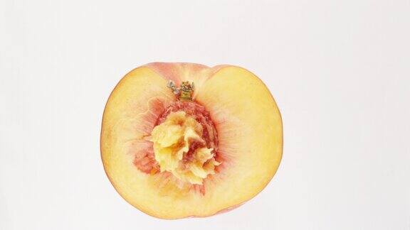 一个被切成两半的桃子在白色背景上旋转
