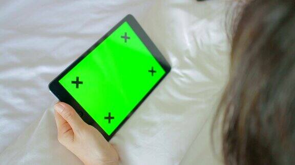 女性在床上使用电子平板电脑绿色屏幕