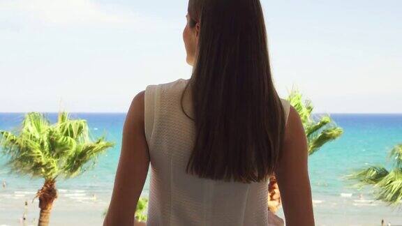 度假的女人拉开窗帘到阳台上欣赏地中海的海景