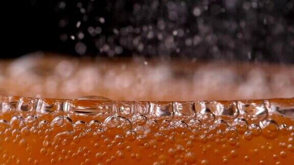 在玻璃杯中冒泡的橙汁汽水-靠近
