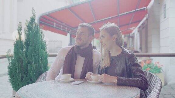 在街头咖啡馆约会的情侣一边喝咖啡一边交流