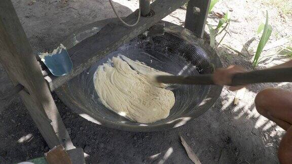 一个农民用一根木棍在炒锅里使棕榈糖变稠的特写