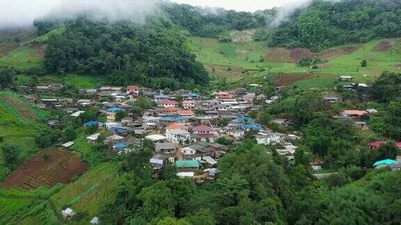 鸟瞰被群山环绕的村庄无人机在泰国北部的乡村城市上空飞行山和雾环绕着这个城市