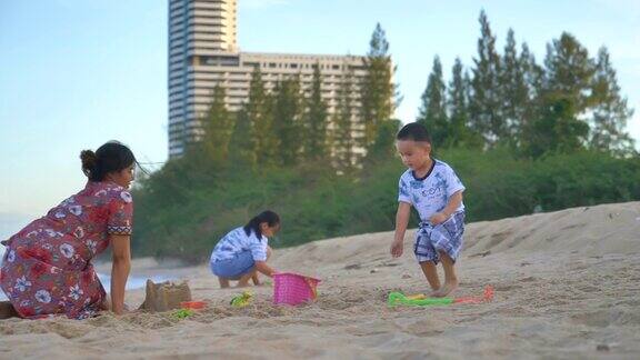 亚洲家庭夏天在海滩上做沙堡的场景慢镜头亚洲家庭暑假在海滩上玩做沙堡概念假期夏天旅游