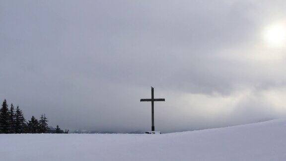 木十字架在雪之上戏剧性的天空与云朵和阳光在冬天时间流逝