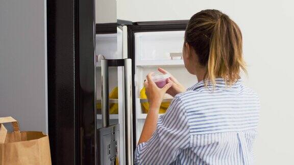 女人把新买的食物放进家里的冰箱