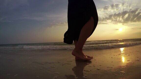 一名女子在日落时分沿着海岸行走的4K视频