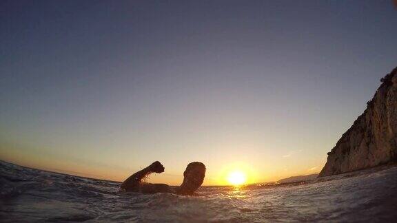 日落时分一个人在水里看着朋友跳下悬崖