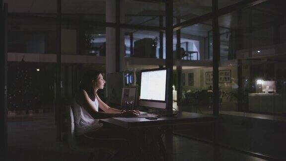 一个年轻的女商人晚上在办公室用电脑工作的4k视频片段