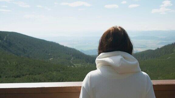 年轻女子走到露台的尽头山谷的迷人景色正在开放