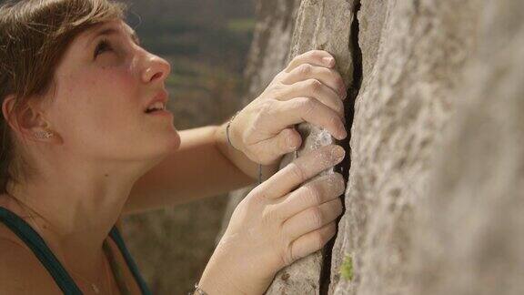 特写:适合女性领头攀登者抓住一个巨大的悬崖上的薄片抓地力