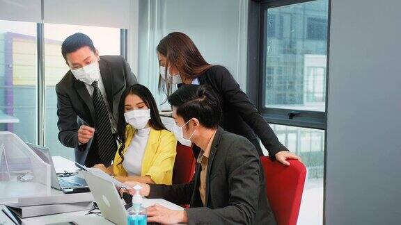 新常态的办公室生活方式亚洲商人和女商人戴着保护面罩社交距离头脑风暴会议一起纸图表和笔记本电脑一起团队成就概念股票视频