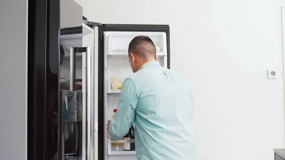从家里厨房冰箱里拿果汁的男人