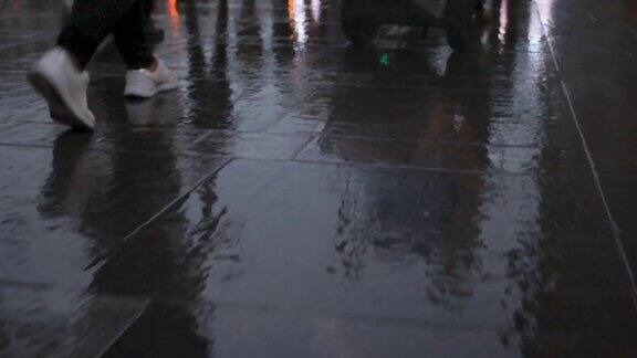 行人的脚步在雨后潮湿的路面上折射出城市的影子