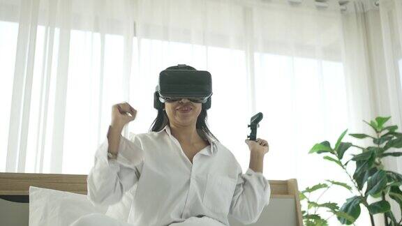 一名年轻女子戴着虚拟现实眼镜玩游戏她呆在卧室里