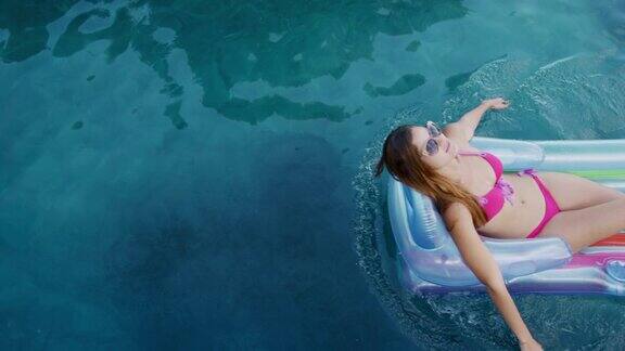 一个白人女人在阳光明媚的日子里享受游泳池
