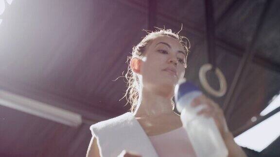 活跃的年轻女子在健身房里从下面喝水在健身中心进行了一场极具挑战性的锻炼后汗流浃背、精疲力竭的运动员开始止渴降温