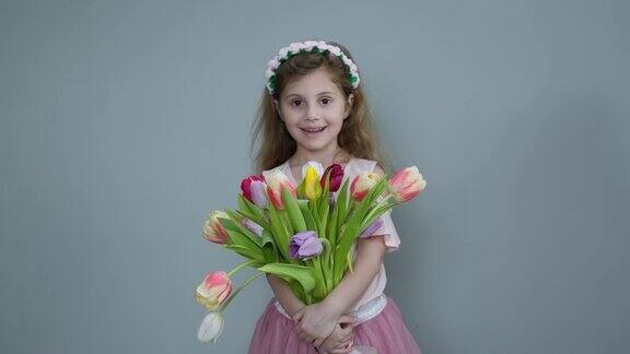 小女孩拿着春天的郁金香花捧花漂亮的小孩拿着一束郁金香小女孩展示一束各式各样的花微笑的女孩拿着一束花