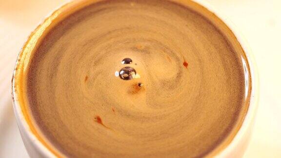 慢镜头:咖啡泡沫在装有咖啡的白色杯中旋转
