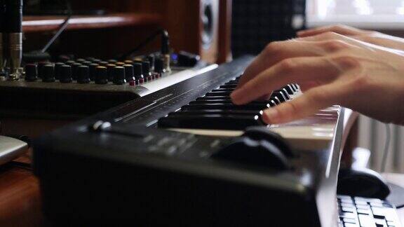 手用电子表在钢琴上弹奏电子键盘音乐录音棚概念在工作室制作歌曲的音乐家歌曲录音过程