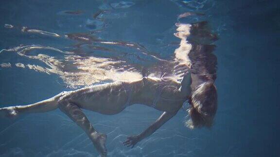 穿着内衣的性感女人漂浮在蓝色的水中