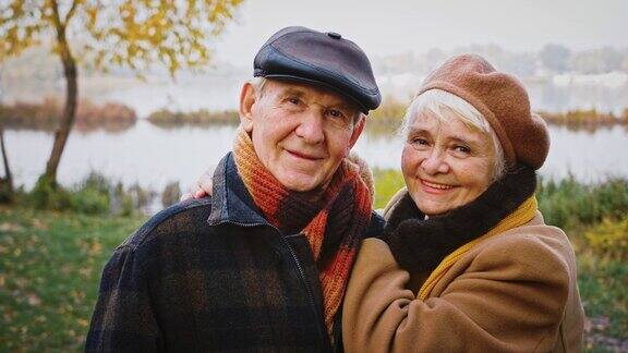 退休的一对爷爷奶奶微笑着带着爱看着你在河边的城市公园摆姿势