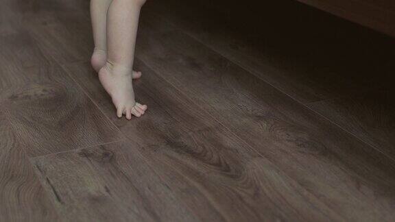 两条光着脚的宝宝站在床边的木地板上