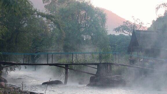 清新的河水在清晨缓缓流过天然的岩石海滩竹桥在河上