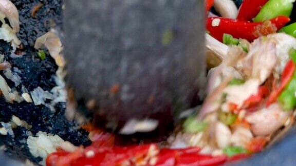用石杵把大蒜和辣椒捣碎在研钵里烹饪泰国菜