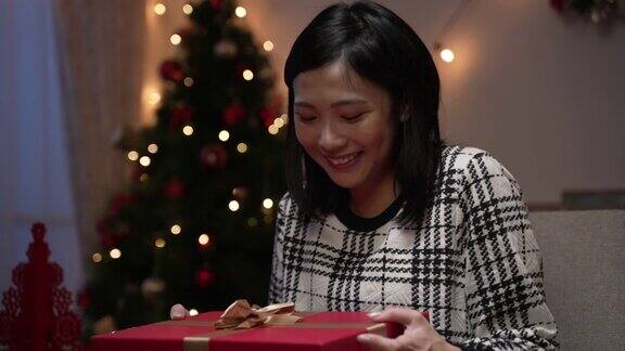 亚洲女性打开她的圣诞礼物是感到沮丧因为得到不想要的东西笑着说感谢的喜悦