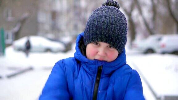 穿着蓝色羽绒服的少年扔雪冬天飘落的雪特写