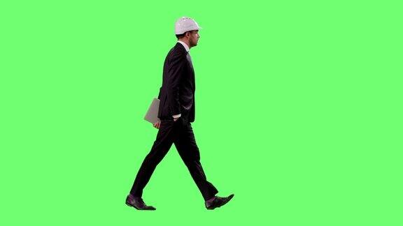 商人戴着安全帽和西装是走在一个模型的绿色屏幕在背景