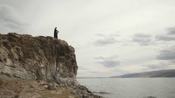 穆斯林女子站在山顶的悬崖边上大湖