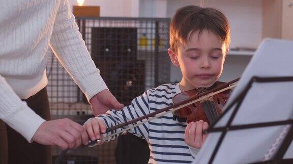 一个年轻女子在教一个小男孩拉小提琴