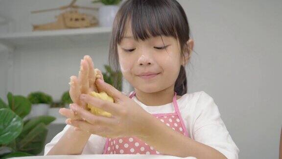 快乐的亚洲孩子在家里一起学习做饼干女孩在她的手中打面团