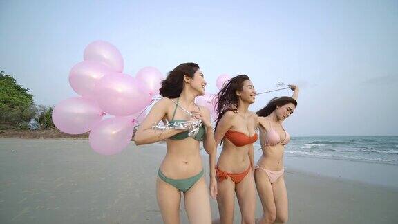 一群快乐的女孩朋友拿着五颜六色的气球在沙滩上奔跑带着快乐的情绪有聚会庆祝观念的人4k决议慢动作镜头