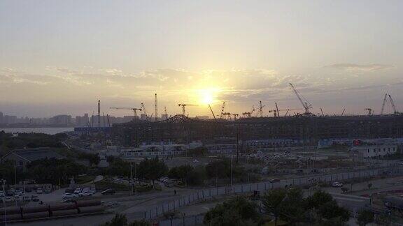 一个大型建筑工地在日落前的背光航拍视频一个巨大的太阳在天空中