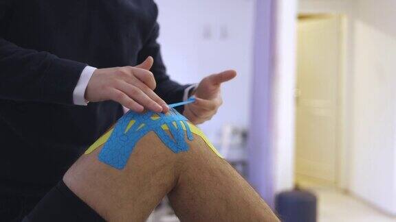 匿名理疗师将肌内肌胶布贴在病人膝盖上