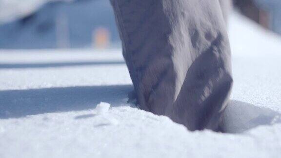近距离的靴子行走在深白的雪在山